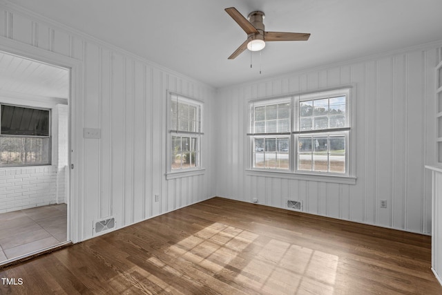 spare room with ceiling fan, wood-type flooring, and brick wall