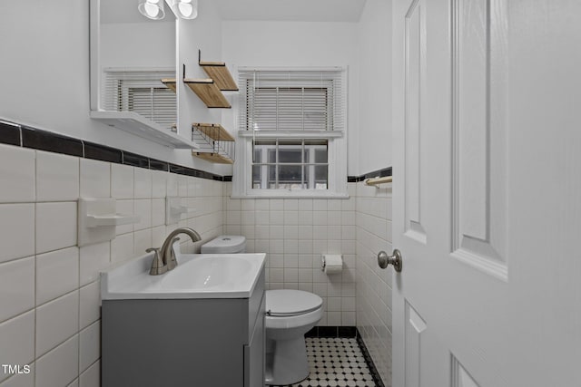 bathroom featuring tile patterned flooring, vanity, toilet, and tile walls