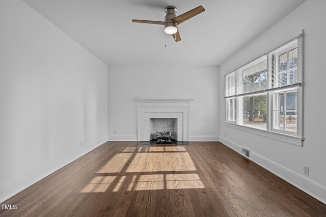 unfurnished living room featuring dark hardwood / wood-style floors, a brick fireplace, and ceiling fan