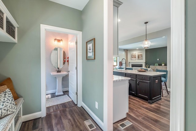 interior space featuring pendant lighting, light stone counters, dark hardwood / wood-style flooring, and sink