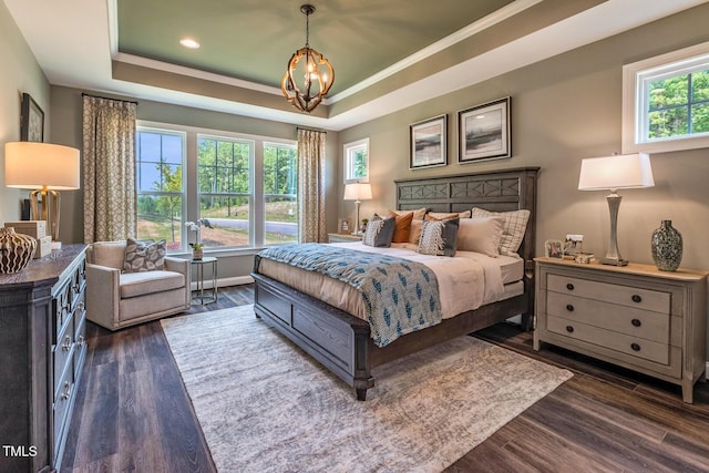 bedroom featuring a tray ceiling, multiple windows, dark wood-type flooring, and a notable chandelier