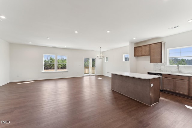 kitchen with dark wood-style flooring, a kitchen island, a sink, visible vents, and tasteful backsplash