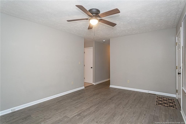 empty room with ceiling fan, dark hardwood / wood-style flooring, and a textured ceiling