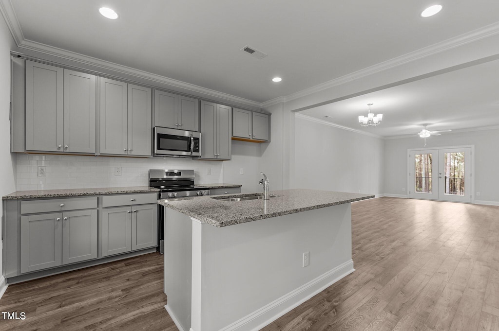 kitchen featuring light stone countertops, sink, wood-type flooring, and appliances with stainless steel finishes