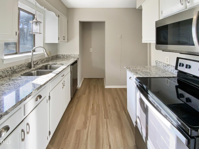 kitchen with sink, light hardwood / wood-style flooring, pendant lighting, white cabinets, and appliances with stainless steel finishes