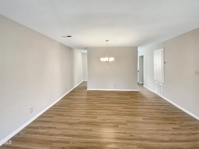 spare room featuring hardwood / wood-style floors and a notable chandelier