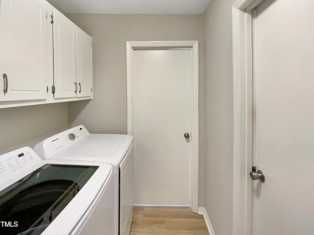 laundry area with cabinets, washer and clothes dryer, and light hardwood / wood-style floors