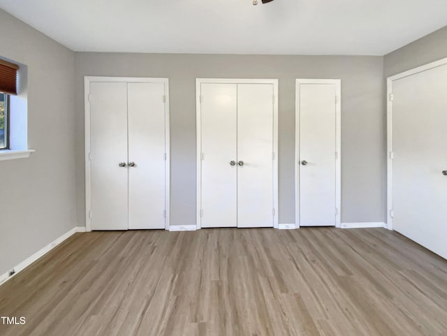 unfurnished bedroom featuring light hardwood / wood-style flooring and two closets