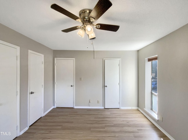 unfurnished bedroom with ceiling fan, light hardwood / wood-style floors, and multiple windows