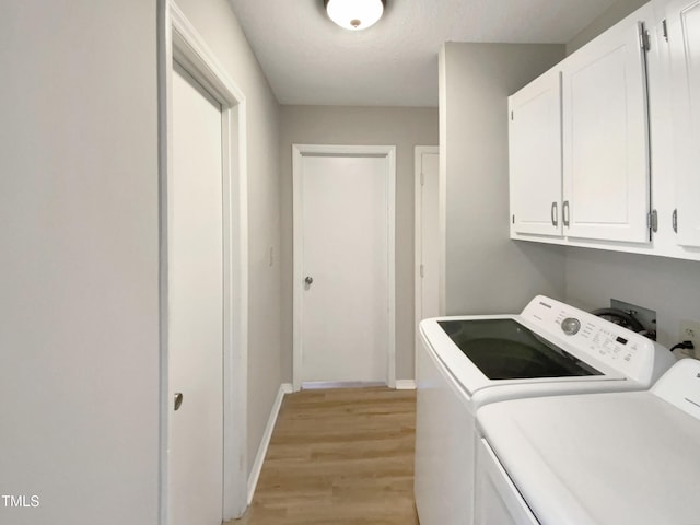 laundry area with cabinets, independent washer and dryer, and light hardwood / wood-style flooring