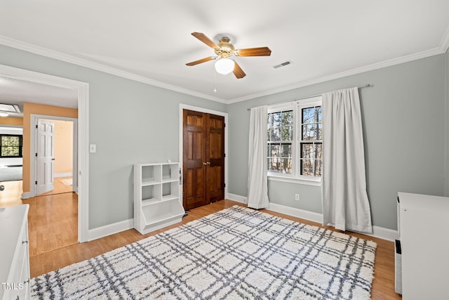 interior space with ceiling fan, crown molding, multiple windows, and light hardwood / wood-style flooring