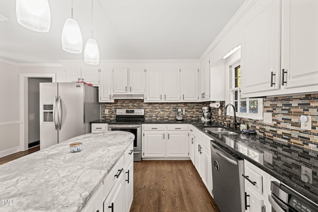 kitchen featuring white cabinetry, stainless steel appliances, decorative light fixtures, dark stone countertops, and sink