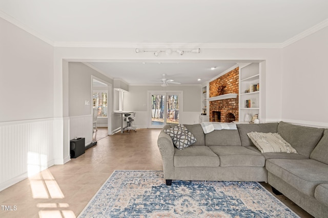 living room featuring ceiling fan, built in features, a fireplace, and ornamental molding