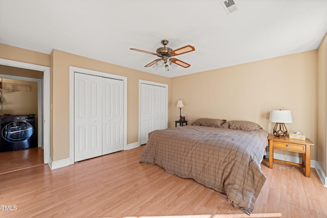 bedroom with ceiling fan, multiple closets, light hardwood / wood-style floors, and washer / clothes dryer