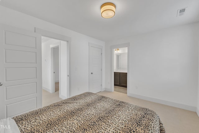 bedroom featuring light carpet, ensuite bath, and a closet