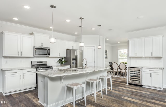 kitchen featuring white cabinets, beverage cooler, appliances with stainless steel finishes, decorative light fixtures, and sink