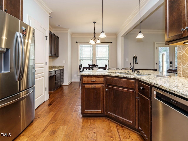 kitchen featuring sink, decorative light fixtures, light wood-type flooring, appliances with stainless steel finishes, and a notable chandelier