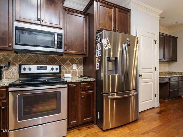 kitchen with light hardwood / wood-style floors, light stone countertops, and appliances with stainless steel finishes