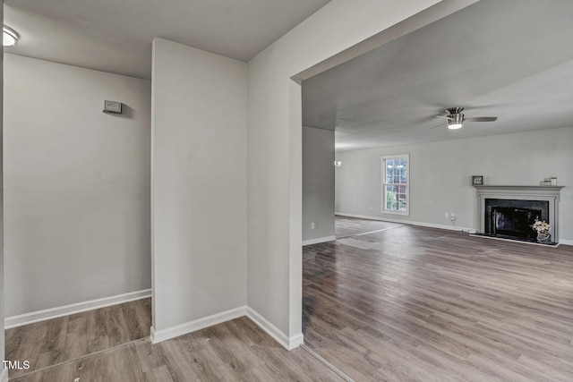 unfurnished living room with ceiling fan, a high end fireplace, and light hardwood / wood-style flooring