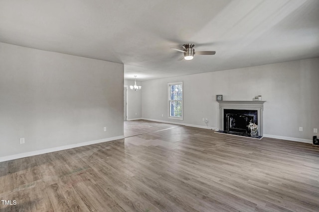 unfurnished living room featuring wood-type flooring and ceiling fan with notable chandelier