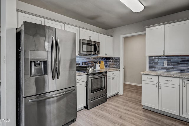 kitchen featuring white cabinets, backsplash, light wood-type flooring, and stainless steel appliances