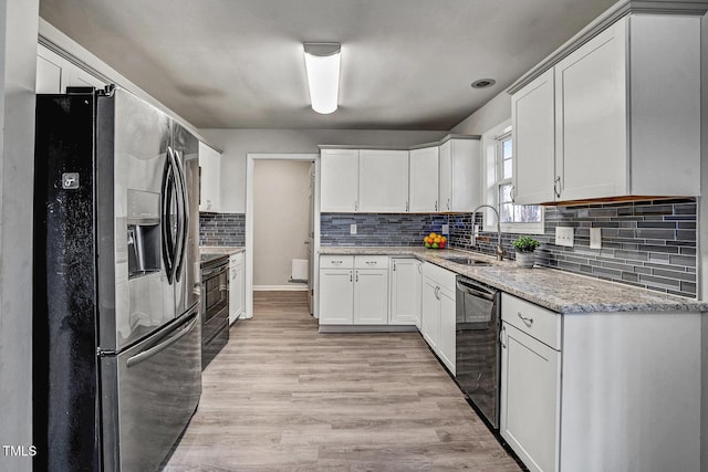 kitchen featuring black appliances, white cabinets, sink, decorative backsplash, and light wood-type flooring