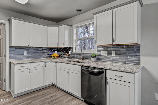 kitchen with light wood-type flooring, white cabinetry, stainless steel dishwasher, and sink