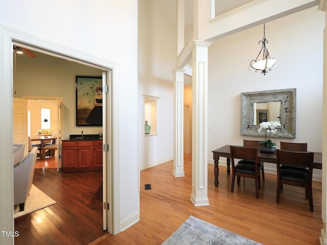 hallway with dark hardwood / wood-style flooring, ornate columns, and a high ceiling