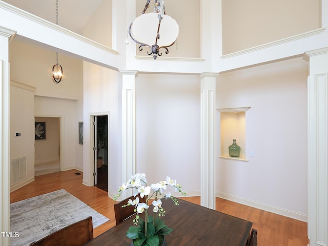 dining space featuring a chandelier, a high ceiling, hardwood / wood-style flooring, and decorative columns