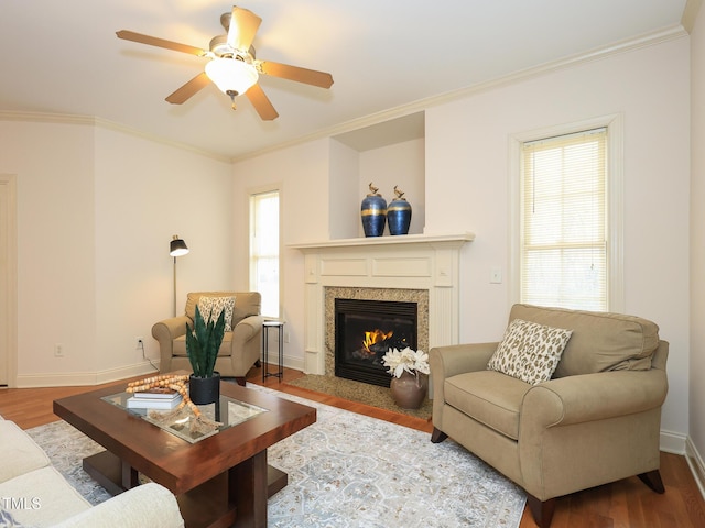 living room with a healthy amount of sunlight, a high end fireplace, ornamental molding, and hardwood / wood-style flooring