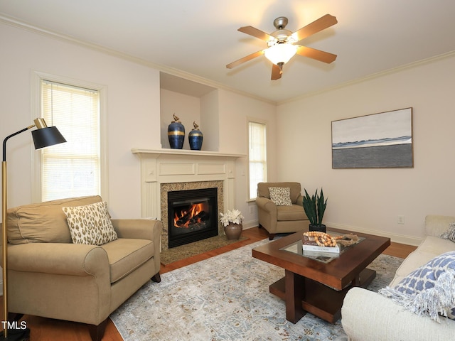 living room with hardwood / wood-style flooring, ceiling fan, ornamental molding, and a premium fireplace