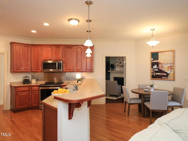 kitchen with a kitchen bar, kitchen peninsula, stainless steel appliances, and hanging light fixtures