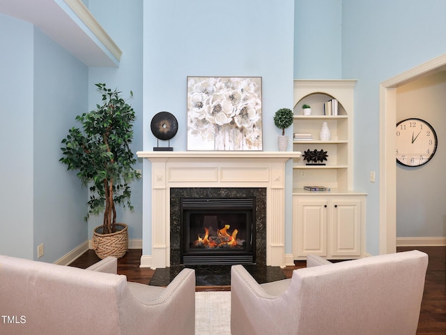 living room with dark hardwood / wood-style floors, a premium fireplace, and built in shelves