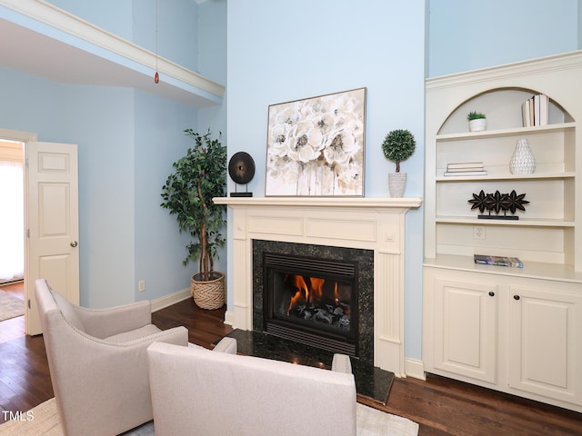 living room featuring a premium fireplace, a high ceiling, and dark hardwood / wood-style floors