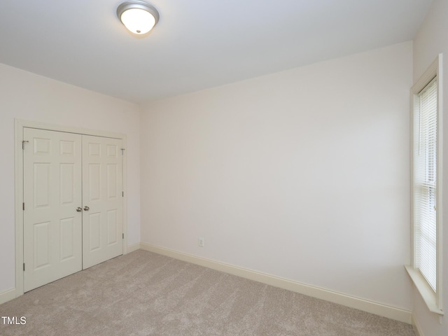 unfurnished bedroom with multiple windows, light carpet, and a closet