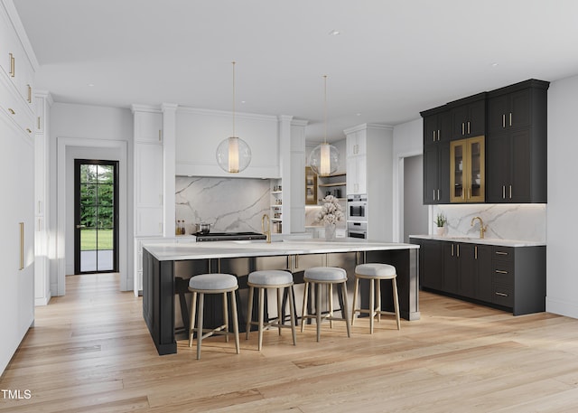 5001 Rampart St, Raleigh, NC 27609 - kitchen with light countertops, backsplash, an island with sink, light wood finished floors, and glass insert cabinets