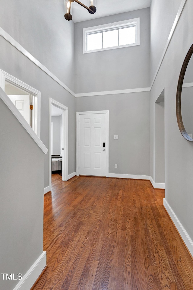 entryway with a high ceiling, radiator heating unit, wood finished floors, and baseboards