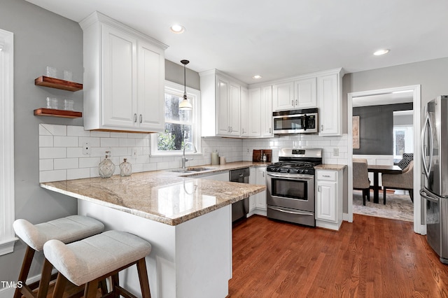 kitchen with a peninsula, white cabinetry, and appliances with stainless steel finishes