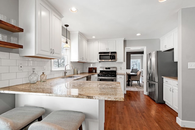 kitchen featuring a peninsula, appliances with stainless steel finishes, a breakfast bar, and white cabinetry