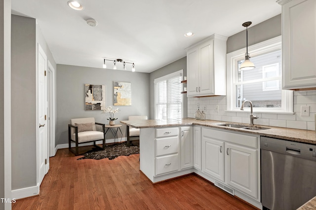 kitchen featuring dishwasher, backsplash, a peninsula, white cabinetry, and a sink