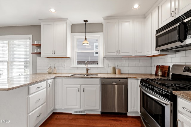 kitchen featuring stainless steel appliances, visible vents, white cabinets, a sink, and light stone countertops