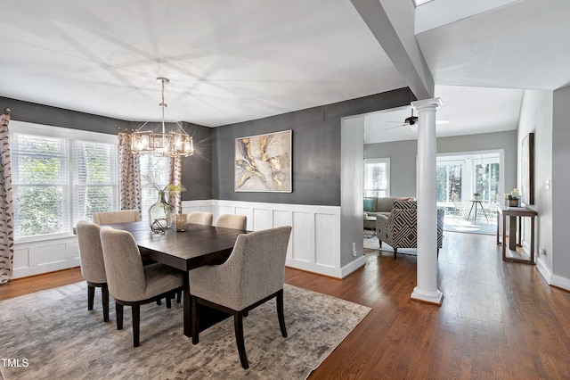 dining room with a decorative wall, a wainscoted wall, dark wood-type flooring, beam ceiling, and ornate columns