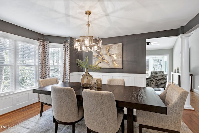 dining space with a healthy amount of sunlight, decorative columns, and wood finished floors