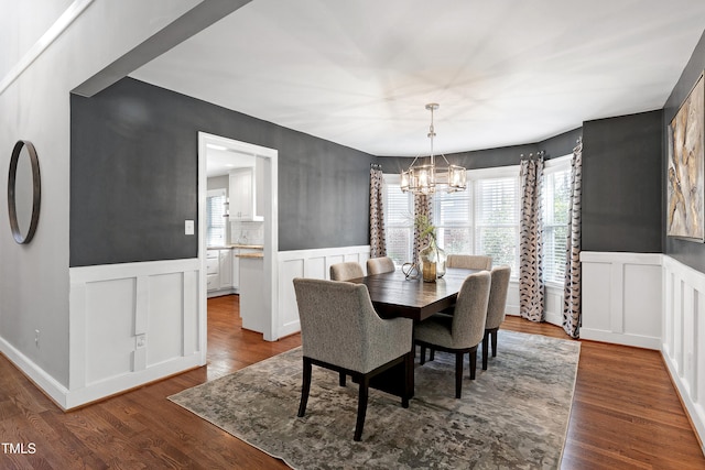 dining room with wainscoting, wood finished floors, and a notable chandelier