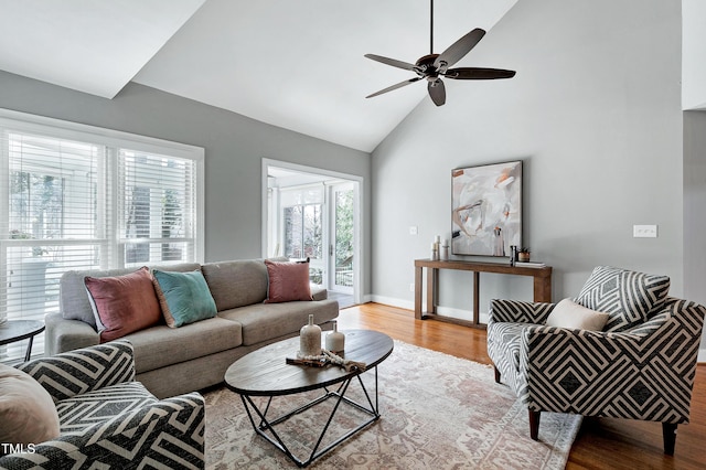 living room with light wood-style floors, high vaulted ceiling, baseboards, and a ceiling fan