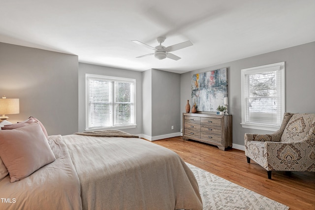 bedroom with ceiling fan, light wood finished floors, and baseboards