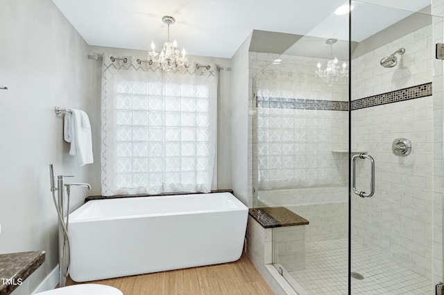 bathroom with a freestanding tub, wood finished floors, a notable chandelier, and a stall shower