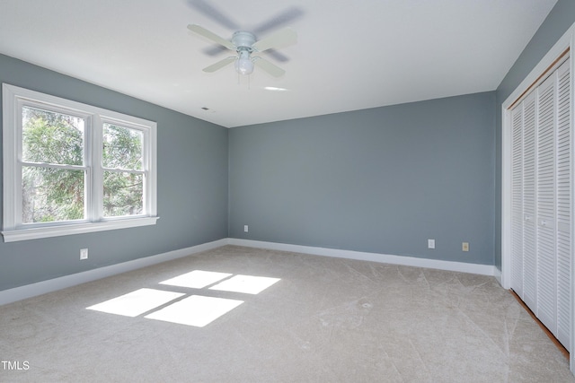 unfurnished bedroom featuring ceiling fan, baseboards, a closet, and light colored carpet