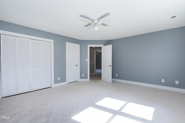 unfurnished bedroom featuring multiple closets, light colored carpet, visible vents, ceiling fan, and baseboards