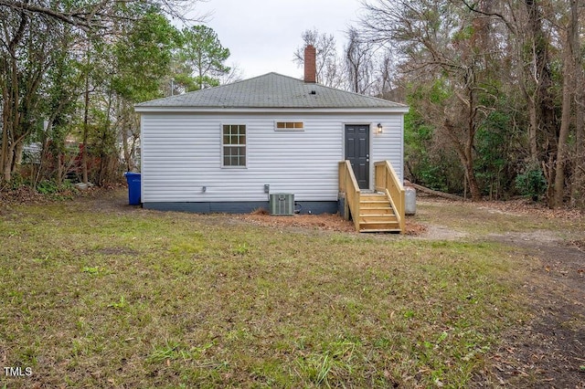 back of property featuring a lawn and central AC